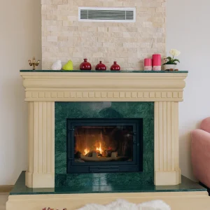 odunlu-somine-model-36-1 Klasik krem çerçeveli, yeşil doğal mermer yüzeye sahip odunlu şömine – oturma odasında yanan alevle sıcak atmosfer oluşturan doğal mermer detaylı şömine.